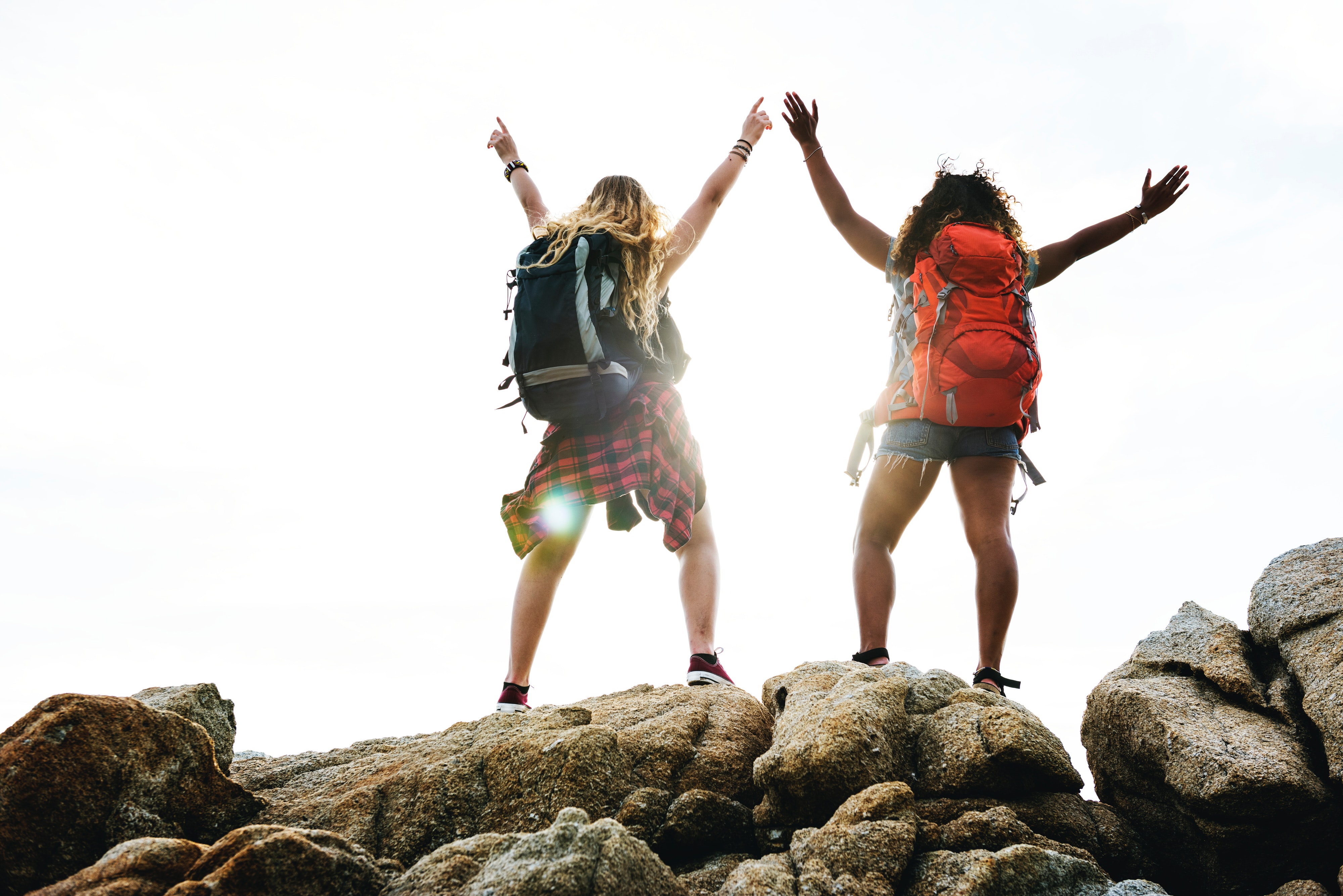 People who have hiked to the top of a mountain and are raising their arms in celebration.