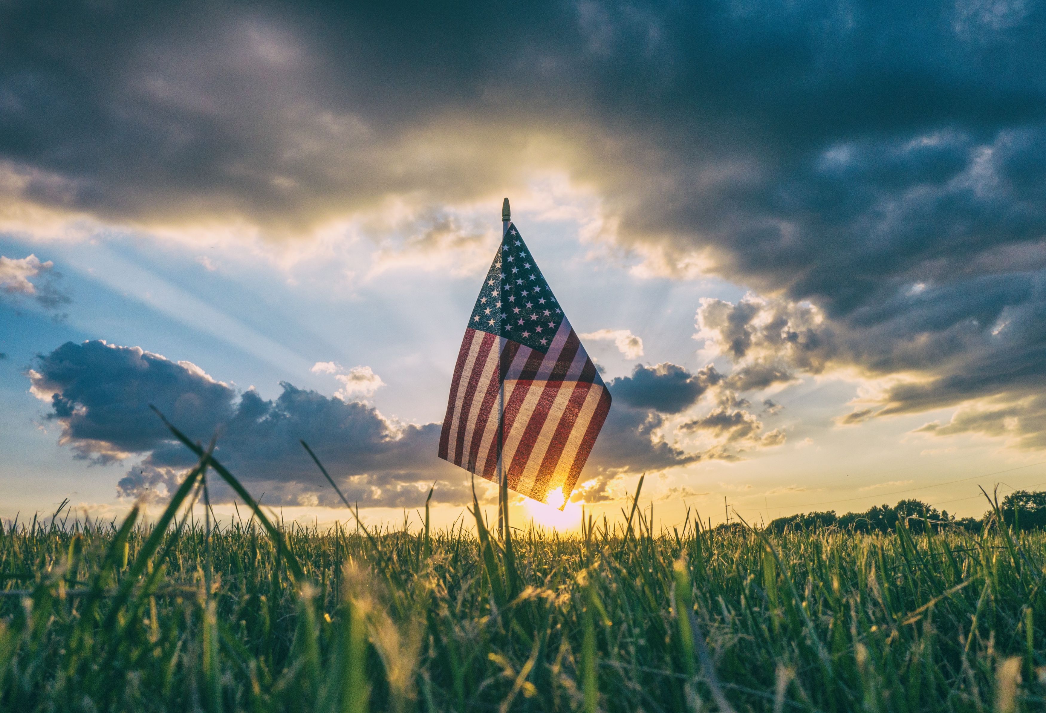 American election flag at sunrise on dewy grass.