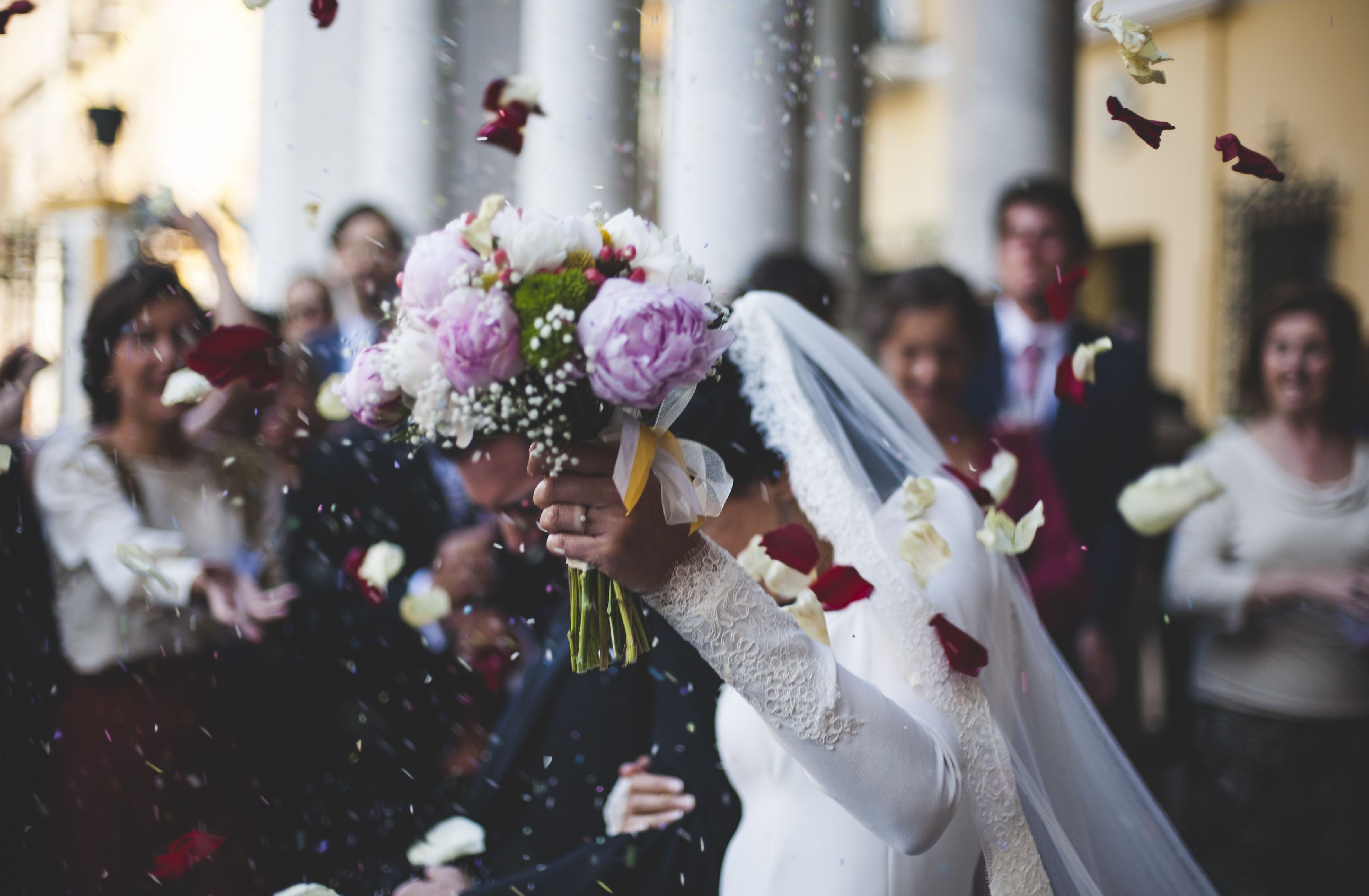Bride and groom leaving wedding reception amidst confetti and flowers.